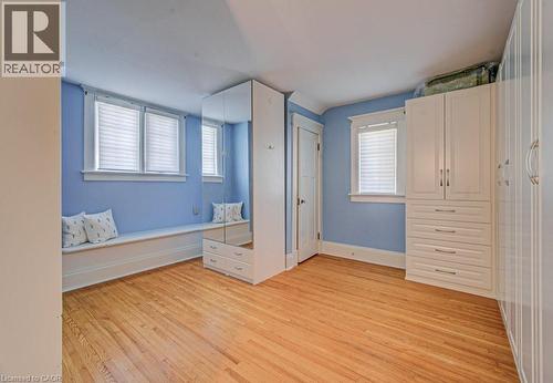 Hardwood flooring throughout this room featuring a built-in window bench with storage, two windows with blinds, a mirrored cabinet, and an additional built-in storage unit with drawers and upper cabin - 2032 Coronation Boulevard, Cambridge, ON - Indoor Photo Showing Other Room