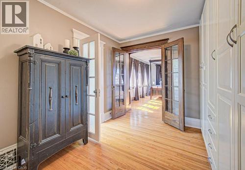 Hardwood flooring complemented by a rich wood-trimmed doorway with glass-paneled double doors - 2032 Coronation Boulevard, Cambridge, ON - Indoor Photo Showing Other Room