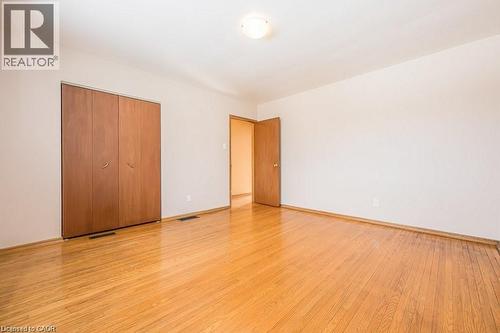 Room featuring wood-finish flooring, a neutral wall palette, a built-in closet with double bifold doors, and a flush mount ceiling light fixture - 66 Summit Avenue, Kitchener, ON - Indoor Photo Showing Other Room