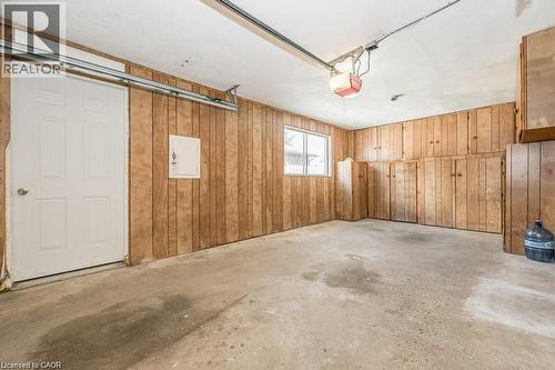 Spacious garage with extensive built-in wood-finish cabinetry, a paneled interior wall, a single window, and a concrete floor - 66 Summit Avenue, Kitchener, ON - Indoor Photo Showing Garage