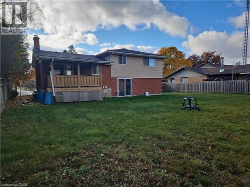 Expansive backyard featuring a manicured lawn, an elevated wood deck with railing, brick exterior, and a sliding glass patio door - 66 Summit Avenue, Kitchener, ON - Outdoor With Deck Patio Veranda