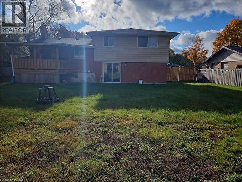 Expansive rear yard featuring a covered wooden deck, brick and siding exterior, sliding glass door, and wooden privacy fence - 66 Summit Avenue, Kitchener, ON - Outdoor