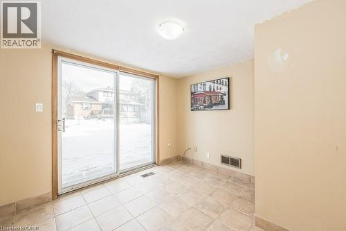 Sliding glass patio doors providing outdoor access, recessed floor vent, and neutral tile flooring with matching base trim - 66 Summit Avenue, Kitchener, ON - Indoor Photo Showing Other Room