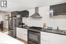Sleek kitchen featuring dark upper cabinetry, white lower cabinetry, dark countertops, and a white subway tile backsplash - 134 Erie Avenue, Hamilton, ON 