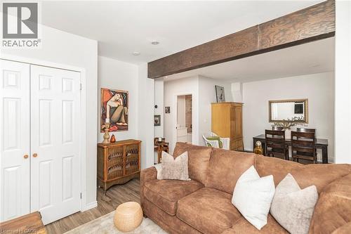 Living area featuring wood-finish flooring, a white six-panel bifold door, and a prominent dark wood beam - 134 Erie Avenue, Hamilton, ON 