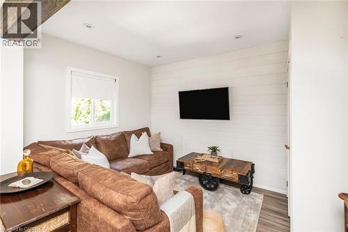 Living area featuring recessed lighting, a white shiplap accent wall, wood-finish flooring, a white window frame, and an exposed ceiling beam - 134 Erie Avenue, Hamilton, ON 