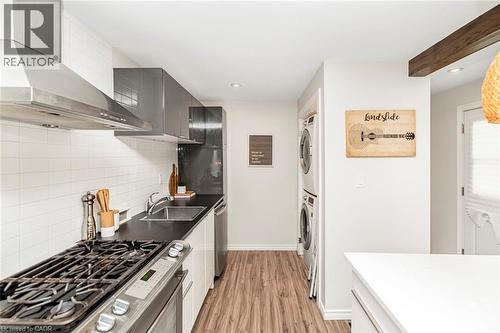 Modern kitchen featuring a stainless steel gas range, coordinating range hood, and white subway tile backsplash - 134 Erie Avenue, Hamilton, ON 