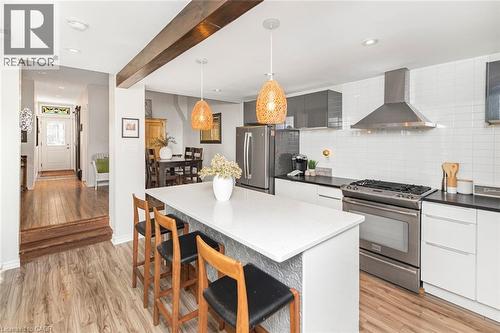 Modern kitchen featuring a white subway tile backsplash, stainless steel appliances, and a central island with a light-toned countertop - 134 Erie Avenue, Hamilton, ON 