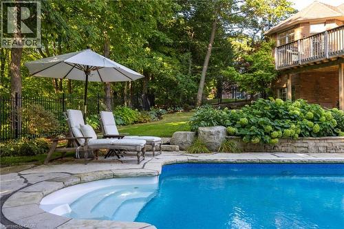 Outdoor swimming pool with integrated steps, stone coping, and surrounding flagstone patio - 1285 Beaufort Drive, Burlington, ON 