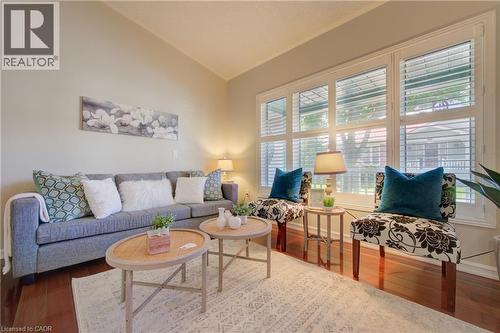 Living area featuring wood-finish flooring, a vaulted ceiling, and white plantation shutters on a large window - 137 Wesley Crescent, Waterloo, ON 