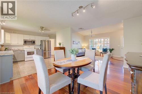 Open-concept interior featuring wood-finish flooring, a kitchen with white cabinetry and stainless steel appliances, a dining area, and a living area with large windows - 137 Wesley Crescent, Waterloo, ON 