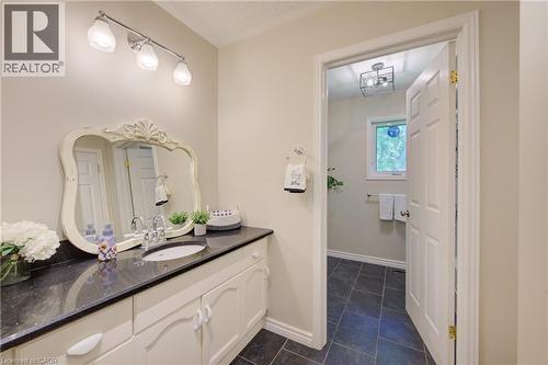 Vanity area featuring a dark countertop, undermount sink, and decorative framed mirror - 137 Wesley Crescent, Waterloo, ON 