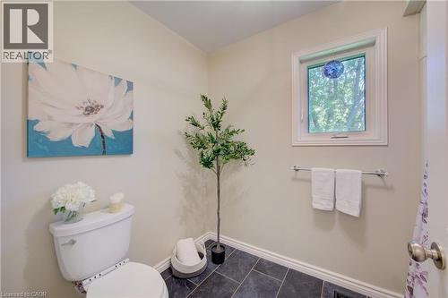 Compact bath with dark tiled flooring, a white toilet, and a single window offering exterior light - 137 Wesley Crescent, Waterloo, ON 