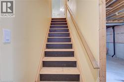 Staircase with light wood stringers, black risers, and a natural wood handrail - 