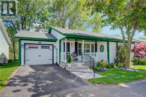 White exterior siding with green trim and a covered front porch featuring white railings - 137 Wesley Crescent, Waterloo, ON 