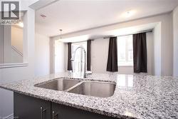 Kitchen island with a double basin stainless steel sink, a chrome gooseneck faucet, and a light-toned granite countertop - 