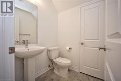 Pedestal sink with chrome faucet, large rectangular mirror, and light gray wood-finish floor tiling - 
