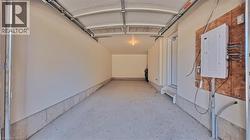 Spacious garage featuring a concrete floor, painted walls, overhead lighting, and an accessible electrical panel - 