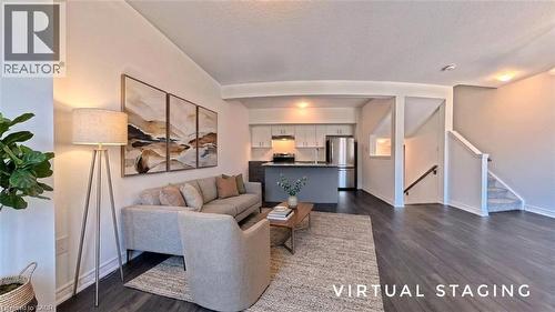 Open-concept living area featuring dark wood-finish flooring, light neutral wall tones, and recessed ceiling lighting - 10 Birmingham Drive Unit# 129, Cambridge, ON - Indoor Photo Showing Living Room