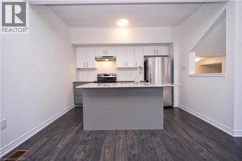 Kitchen featuring a central island with a granite-style countertop, white cabinetry with brushed nickel hardware, and stainless steel appliances - 10 Birmingham Drive Unit# 129, Cambridge, ON - Indoor Photo Showing Kitchen With Stainless Steel Kitchen With Upgraded Kitchen
