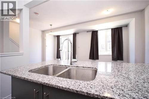 Kitchen island with a double basin stainless steel sink, a chrome gooseneck faucet, and a light-toned granite countertop - 10 Birmingham Drive Unit# 129, Cambridge, ON - Indoor Photo Showing Kitchen With Double Sink