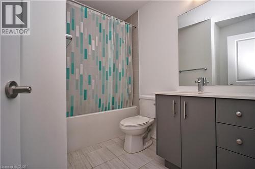 Bathroom featuring a white tub, toilet, and a vanity with gray cabinetry and a light-toned countertop - 10 Birmingham Drive Unit# 129, Cambridge, ON - Indoor Photo Showing Bathroom