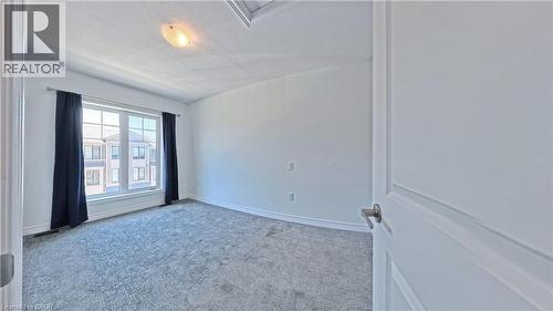 Bright interior room featuring a large window with white trim, gray carpet, white walls, and a semi-flush ceiling light - 10 Birmingham Drive Unit# 129, Cambridge, ON - Indoor Photo Showing Other Room