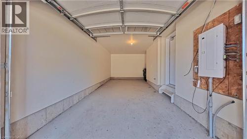 Spacious garage featuring a concrete floor, painted walls, overhead lighting, and an accessible electrical panel - 10 Birmingham Drive Unit# 129, Cambridge, ON - Indoor
