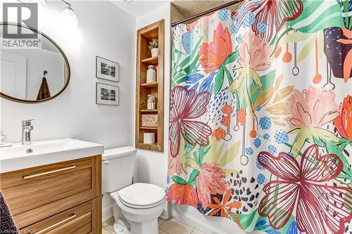 Bathroom featuring a wood-finish vanity with an integrated sink, a circular mirror, and an in-wall wood-finish shelving unit - 218 Richardson Drive Unit# 26, Port Dover, ON 