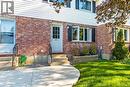 Brick and siding exterior featuring multiple entry doors, a curved concrete walkway, and established landscaping with a wooden planter box - 218 Richardson Drive Unit# 26, Port Dover, ON 