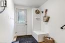 Entryway featuring a white door with frosted glass panels, wood-finish flooring, a built-in white bench, a built-in wall panel with a shelf, and wall-mounted coat hooks - 218 Richardson Drive Unit# 26, Port Dover, ON 