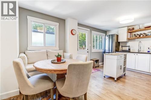 Eat-in kitchen featuring wood-finish flooring, white cabinetry, open shelving, a stainless steel refrigerator, and a built-in banquette - 218 Richardson Drive Unit# 26, Port Dover, ON 