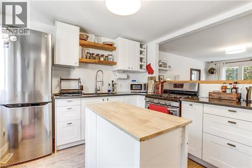 Bright kitchen featuring white cabinetry, dark countertops, a stainless steel refrigerator, and a central island with a wood-finish top - 218 Richardson Drive Unit# 26, Port Dover, ON 