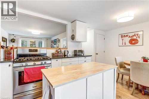 Kitchen featuring an island with a wood-finish countertop, stainless steel gas range, white cabinetry, dark countertops, and wood-finish flooring - 218 Richardson Drive Unit# 26, Port Dover, ON 
