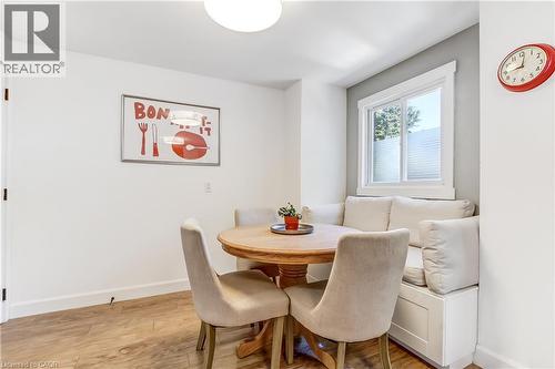 Breakfast nook featuring a built-in bench with upholstered cushions, a round wood-finish table, and wood-finish flooring - 218 Richardson Drive Unit# 26, Port Dover, ON 