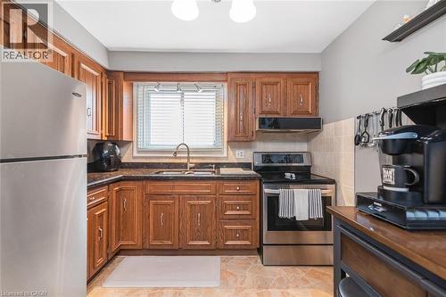 Kitchen featuring wood cabinetry, stainless steel appliances, dark stone countertops, and a tile backsplash - 366 Berkindale Drive, Hamilton, ON 