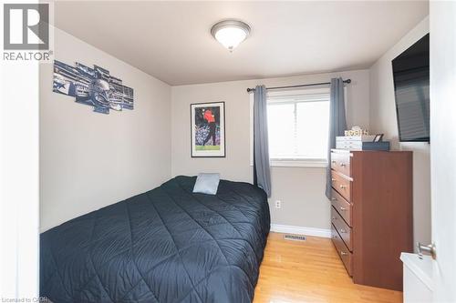 Bedroom featuring wood-finish flooring, a window with blinds, and a flush-mount ceiling light fixture - 366 Berkindale Drive, Hamilton, ON 