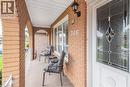 Covered front porch featuring arched brickwork, a decorative glass entry door, white window blinds, an exterior wall sconce, and a white metal railing - 366 Berkindale Drive, Hamilton, ON 