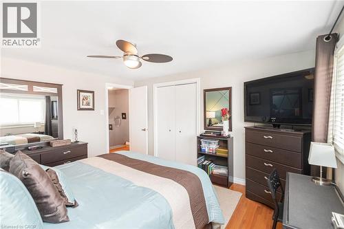 Bedroom featuring light wood-finish flooring, a ceiling fan with integrated lighting, and a window with blinds - 366 Berkindale Drive, Hamilton, ON 