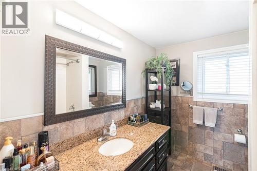 Bathroom vanity featuring a light-toned granite countertop, undermount sink, and dark wood cabinetry - 366 Berkindale Drive, Hamilton, ON 