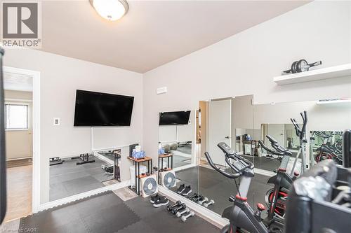 Dedicated fitness space featuring a full-wall mirror, mounted television, and recessed lighting - 366 Berkindale Drive, Hamilton, ON 