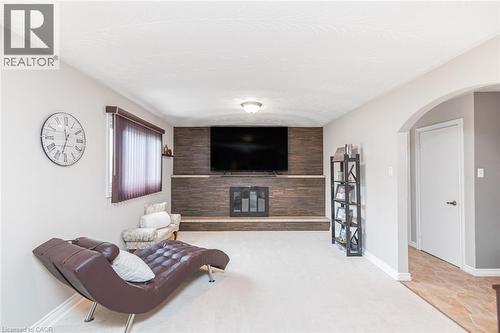 Carpeted living area featuring a central fireplace with wood-finish paneling, a recessed hearth, and an integrated mantel - 366 Berkindale Drive, Hamilton, ON 