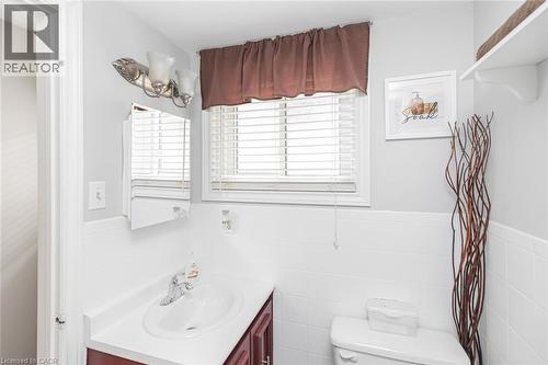 Bathroom featuring a window with blinds, a vanity with an integrated sink, a wall-mounted medicine cabinet, and a two-bulb light fixture - 366 Berkindale Drive, Hamilton, ON 