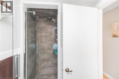 Shower enclosure featuring dark grey rectangular tile, a multi-function showerhead, and a glass panel door with a chrome handle - 366 Berkindale Drive, Hamilton, ON 