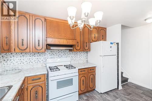 Kitchen featuring wood cabinetry, white appliances, a white gas range, and a patterned tile backsplash - 366 Berkindale Drive, Hamilton, ON 