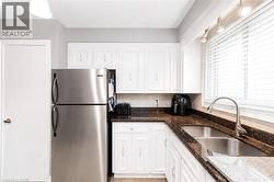 Kitchen featuring white cabinetry, dark stone countertops, and stainless steel appliances - 