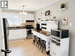 Kitchen featuring white cabinetry, stone-finish countertops, and stainless steel appliances - 