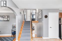 Multi-level interior featuring a carpeted staircase with wood-finish risers, an arched entryway, and neutral wall tones - 
