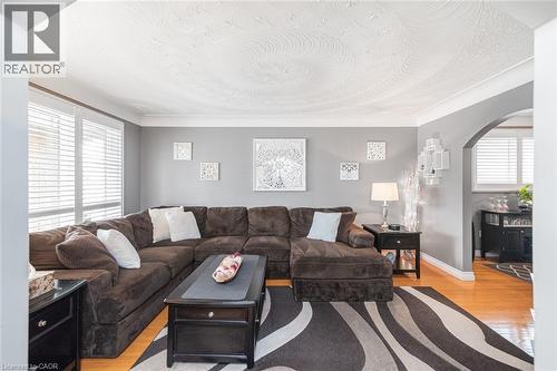 Living area featuring wood-finish flooring, bay windows with blinds, an arched doorway, and crown molding - 366 Berkindale Drive, Hamilton, ON 