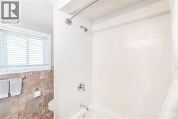 Shower-over-tub combination with white subway tile surround, chrome fixtures, and a curved shower rod - 
